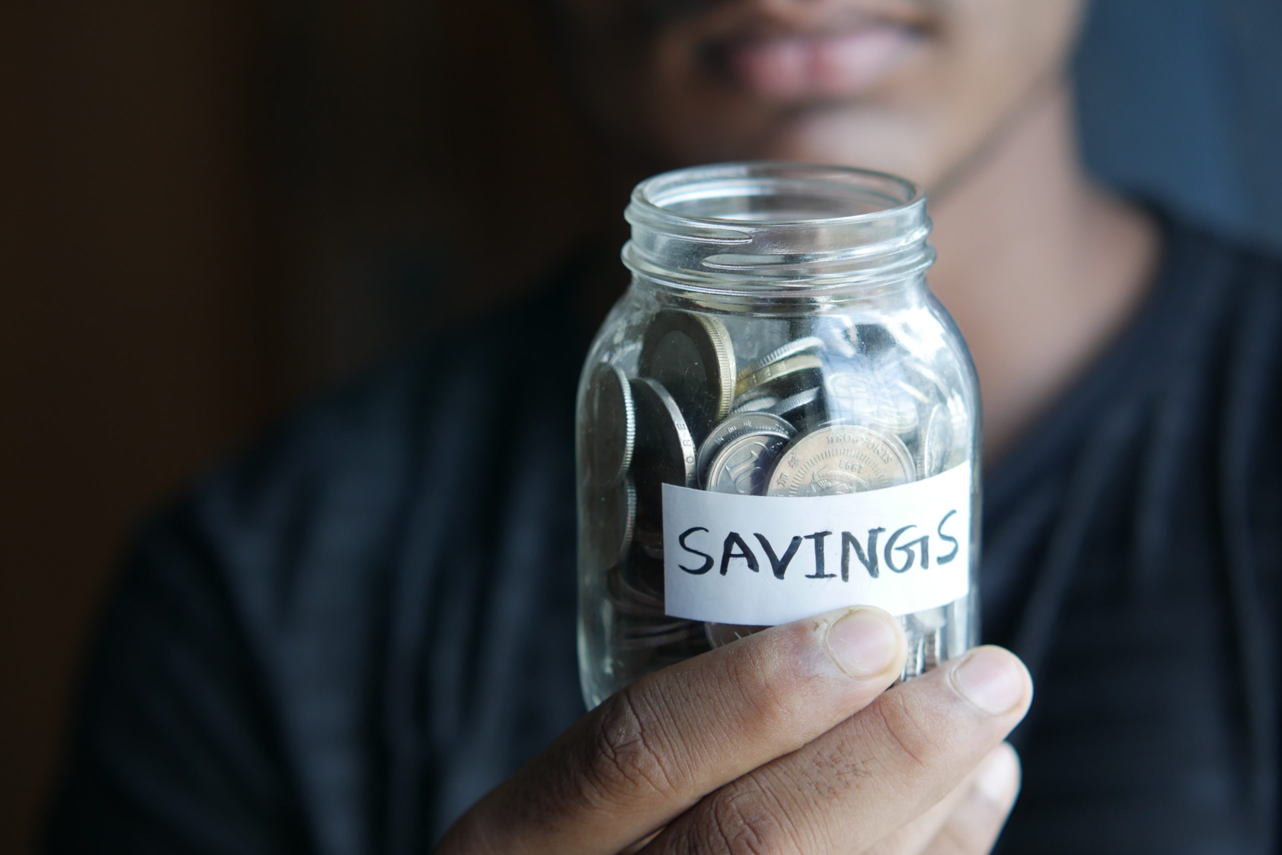 person holding a jar full of money labelled savings