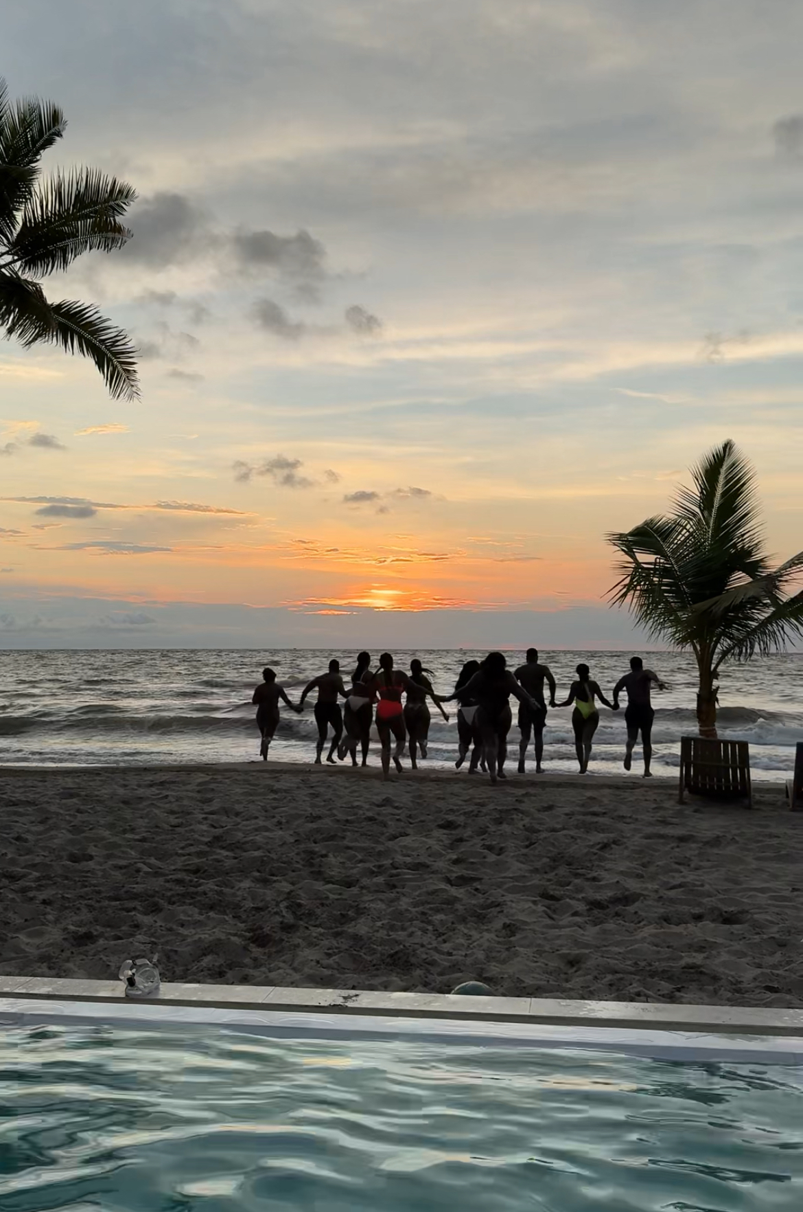 Group of friends holding hands running on the beach